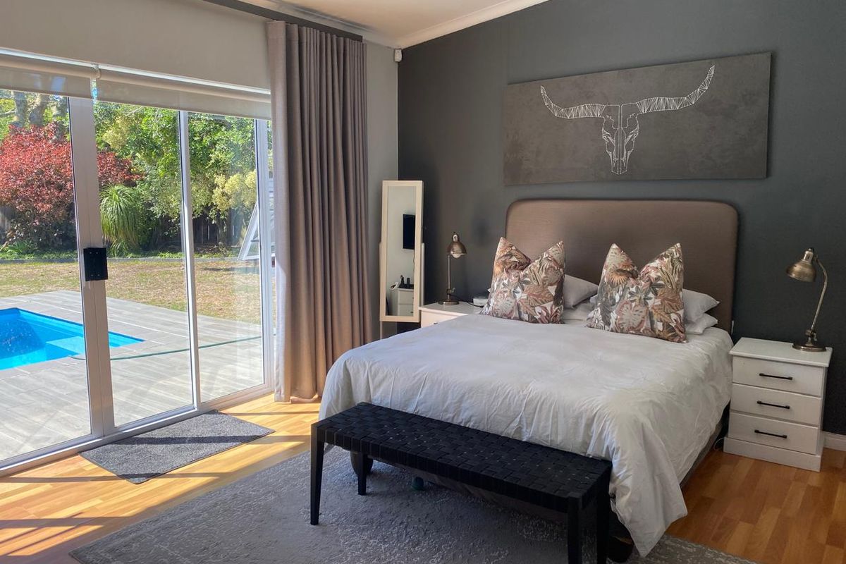 A well-maintained bedroom featuring laminate flooring and a large sliding glass door providing direct access to the patio and pool area.