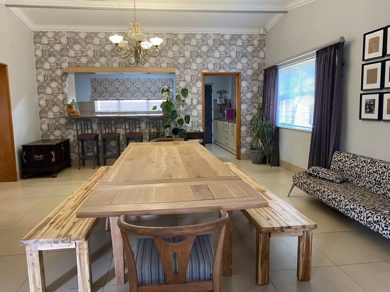 Spacious dining room featuring patterned wallpaper, tiled flooring, and a convenient pass-through window connecting to the kitchen area.