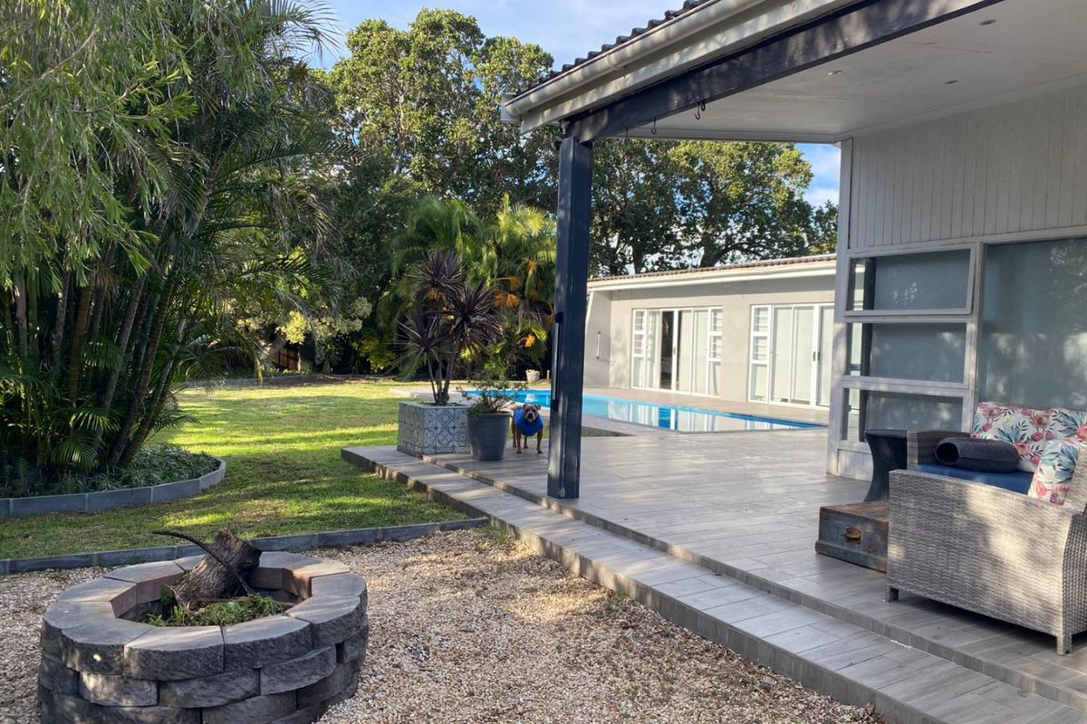 A spacious rear garden featuring a tiled patio, a built-in stone fire pit, and a swimming pool, perfect for outdoor entertaining.