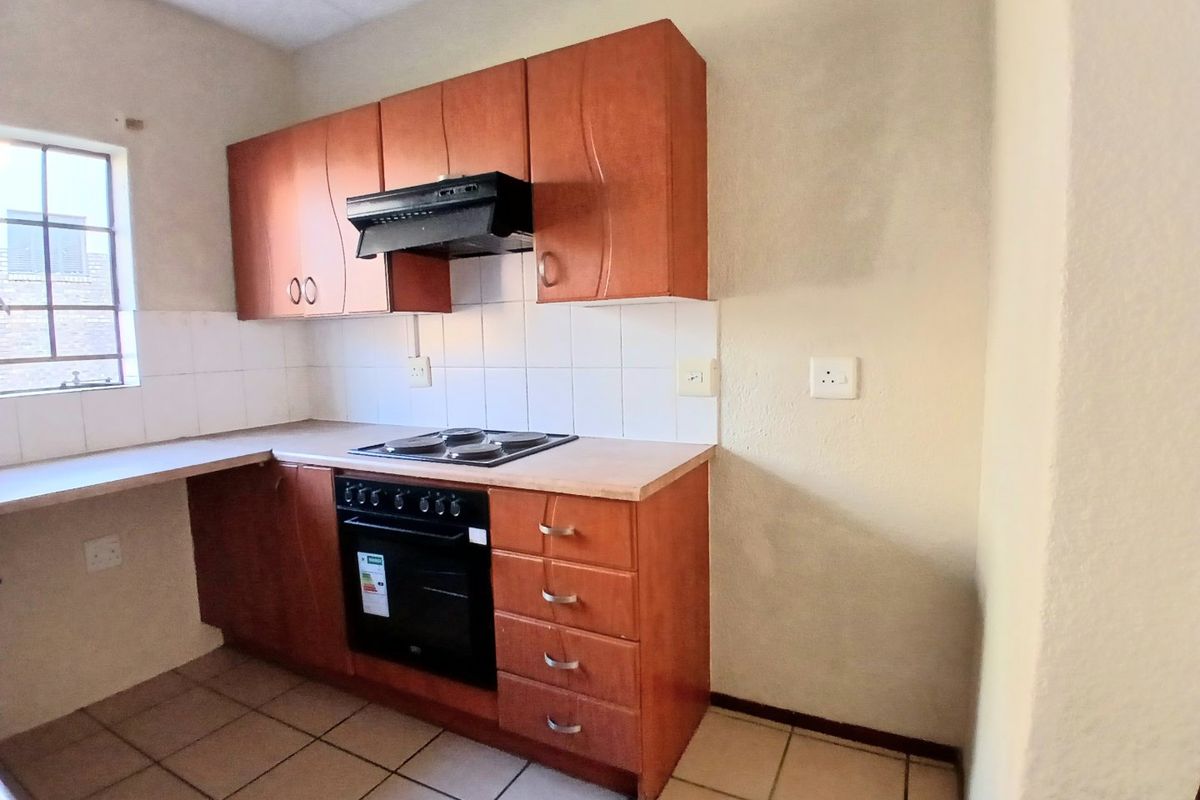 A functional kitchen featuring built-in wooden cabinetry, laminate countertops, an integrated oven, and an electric hob with an extractor fan.