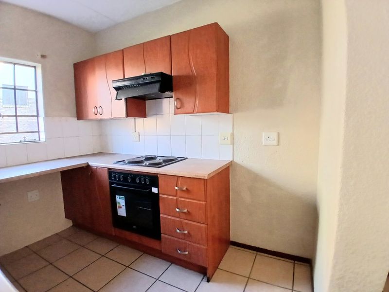 A functional kitchen featuring built-in wooden cabinetry, laminate countertops, an integrated oven, and an electric hob with an extractor fan.