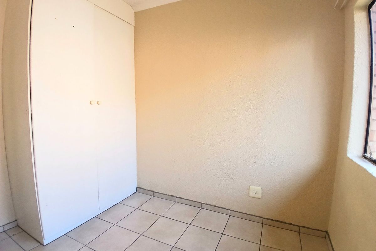 An empty bedroom featuring tiled flooring and a built-in wardrobe, providing a blank canvas for personalization.