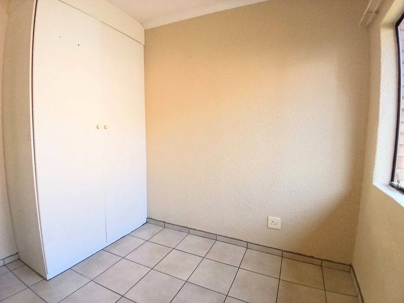 An empty bedroom featuring tiled flooring and a built-in wardrobe, providing a blank canvas for personalization.