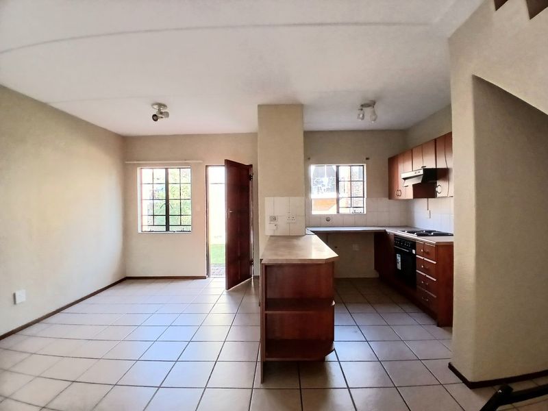 Open-plan living and kitchen area featuring tiled floors, built-in wooden cabinetry, and direct access to an outdoor space.
