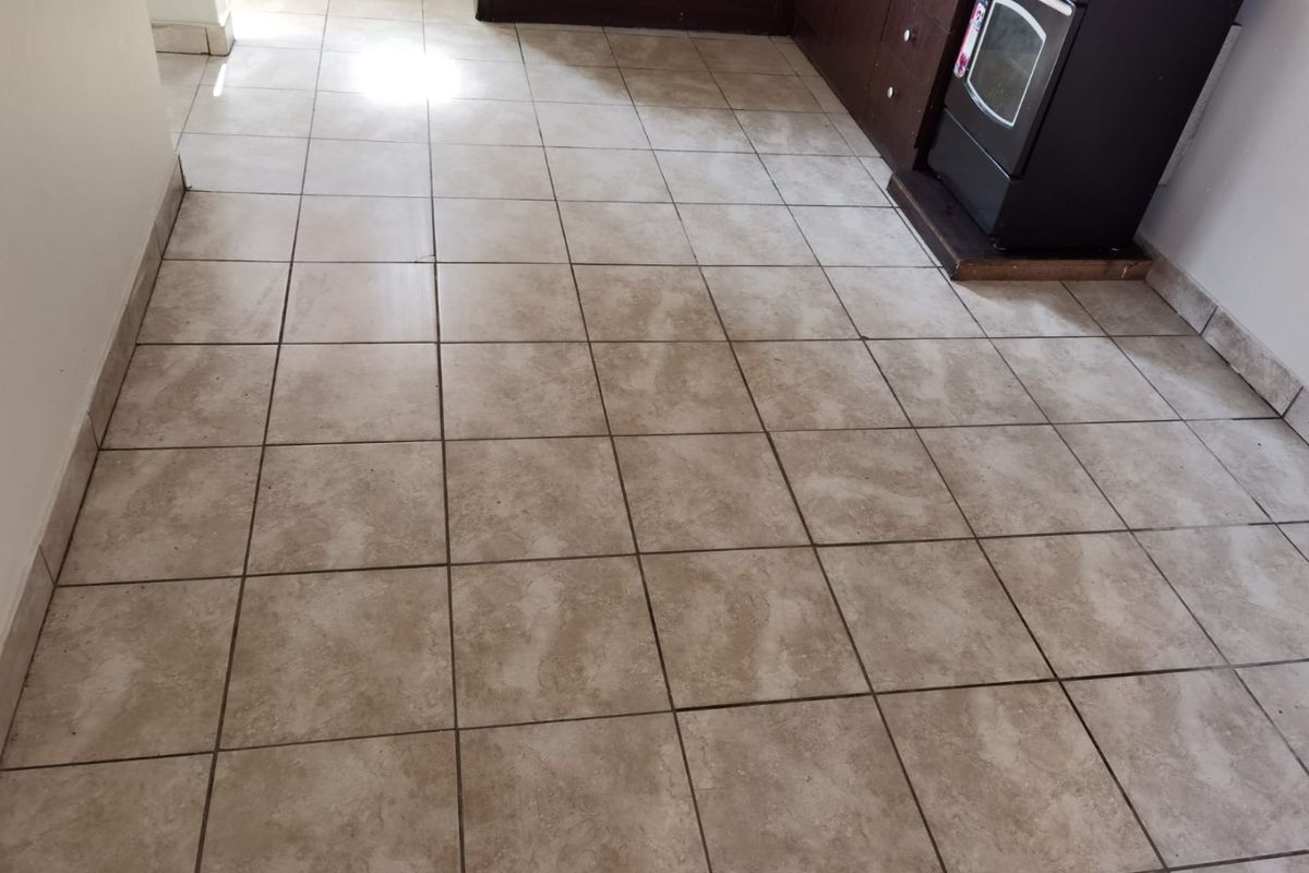 A functional kitchen area featuring tiled flooring and built-in cabinetry with a freestanding oven, presenting a dated aesthetic in need of cosmetic updates.