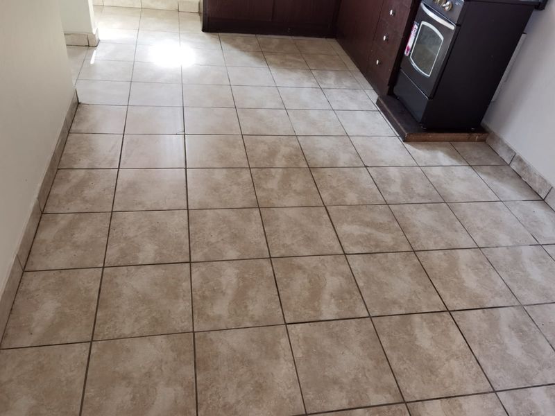 A functional kitchen area featuring tiled flooring and built-in cabinetry with a freestanding oven, presenting a dated aesthetic in need of cosmetic updates.