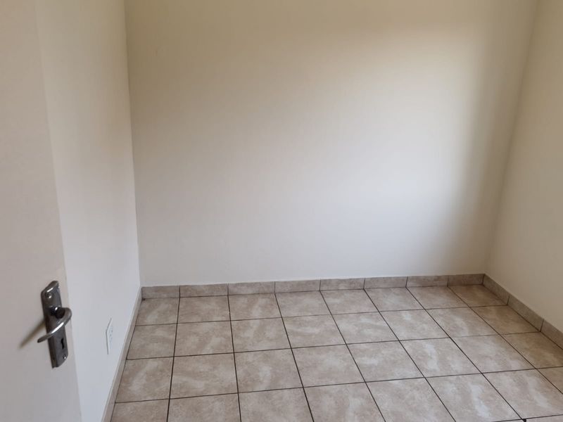 A clean, empty bedroom featuring neutral wall paint and durable tiled flooring, providing a blank canvas for personalization.