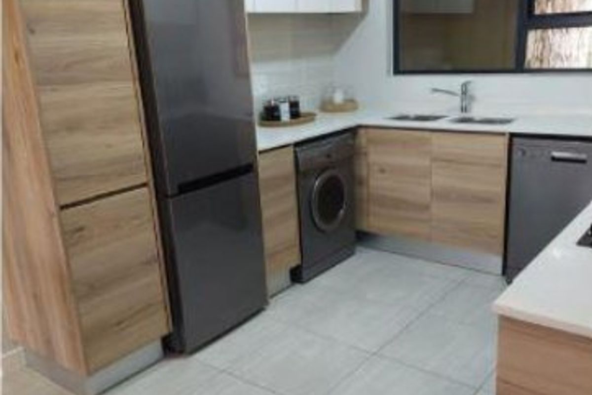 Modern kitchen featuring wood-grain cabinetry, stone countertops, double sink, and tiled flooring with integrated appliance spaces.