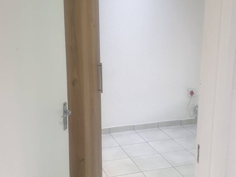An empty bedroom featuring tiled flooring and a built-in wooden wardrobe, offering a clean and neutral space ready for personalization.