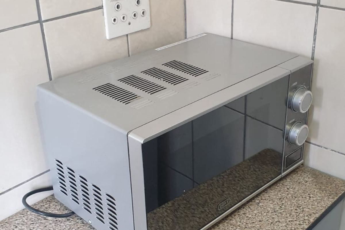A close-up view of a kitchen countertop area featuring tiled splashbacks, built-in cabinetry, and an electrical outlet.