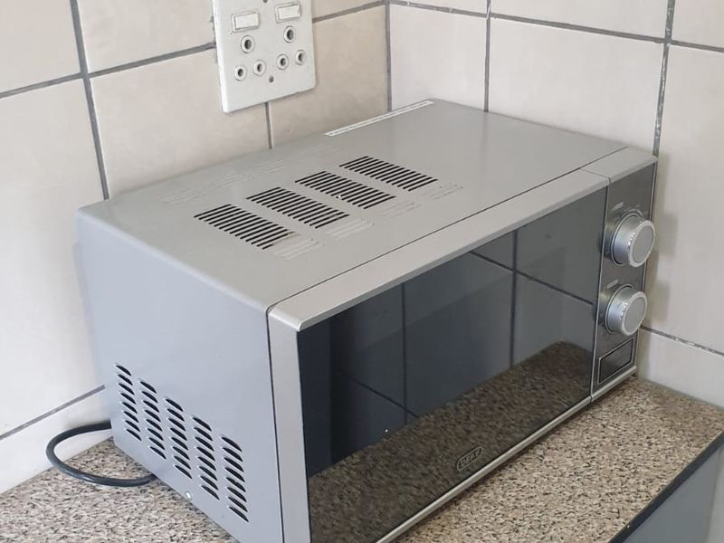 A close-up view of a kitchen countertop area featuring tiled splashbacks, built-in cabinetry, and an electrical outlet.