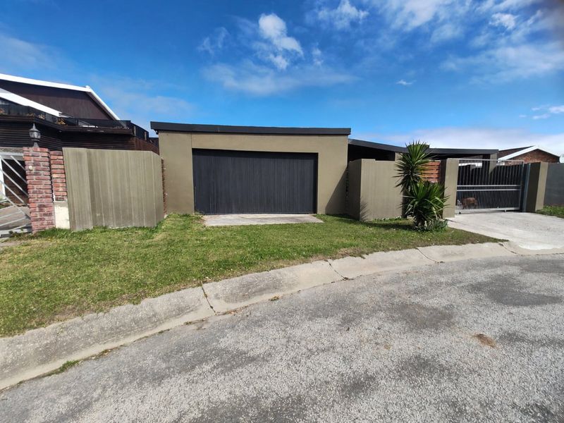 Front view of the property featuring a modern garage door, boundary wall, and gated driveway access from the street.