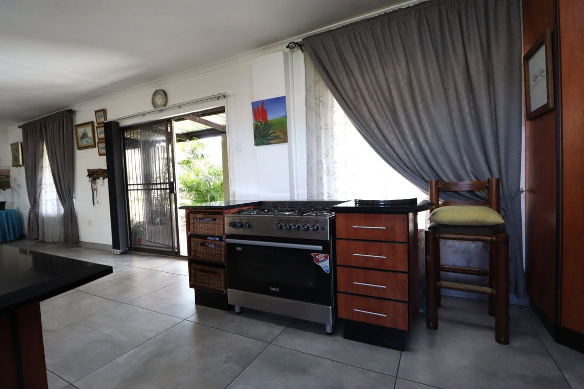 Kitchen area featuring a stainless steel gas stove, built-in cabinetry with granite countertops, and tiled flooring, with direct access to an outdoor patio.