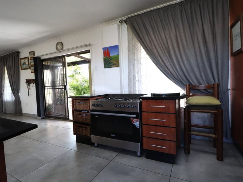 Kitchen area featuring a stainless steel gas stove, built-in cabinetry with granite countertops, and tiled flooring, with direct access to an outdoor patio.
