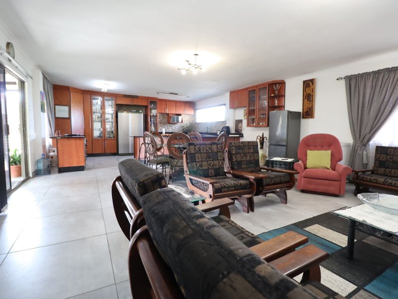 Spacious open-plan living and kitchen area featuring tiled flooring, extensive built-in cabinetry, and direct access to the outdoor patio through sliding glass doors.