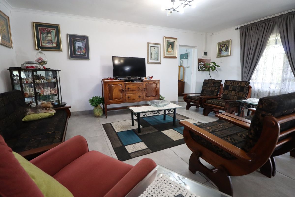 A spacious living room featuring neutral tiled flooring and classic ceiling cornicing, providing a functional and well-lit area for relaxation.