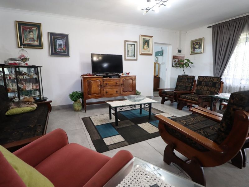 A spacious living room featuring neutral tiled flooring and classic ceiling cornicing, providing a functional and well-lit area for relaxation.