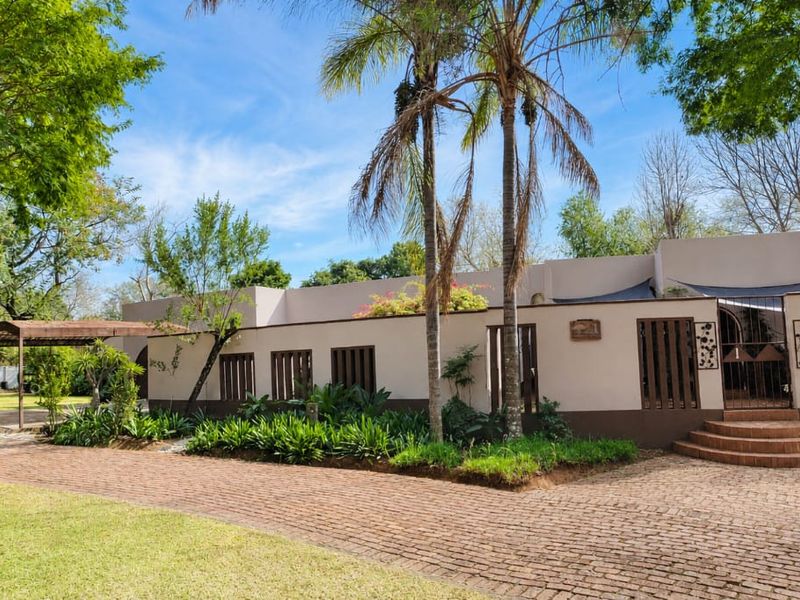 Front elevation of a single-story house featuring a brick driveway, carport, landscaped garden, and a welcoming entrance with brick steps and security gate.