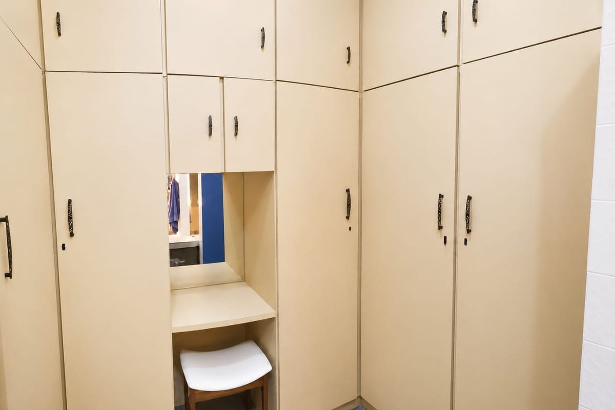 A bedroom featuring extensive floor-to-ceiling built-in cupboards with an integrated vanity station and mirror.