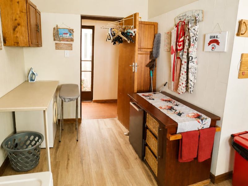 A functional laundry area featuring laminate flooring, built-in cabinetry, and direct access to an adjacent space.