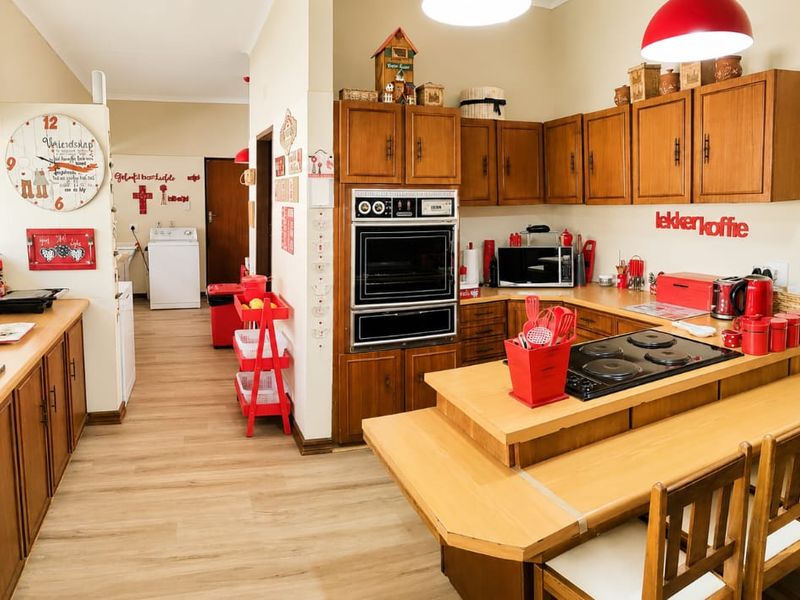 Spacious kitchen featuring traditional wooden cabinetry, a built-in double oven, electric hob, and an integrated breakfast counter with wood-look flooring.