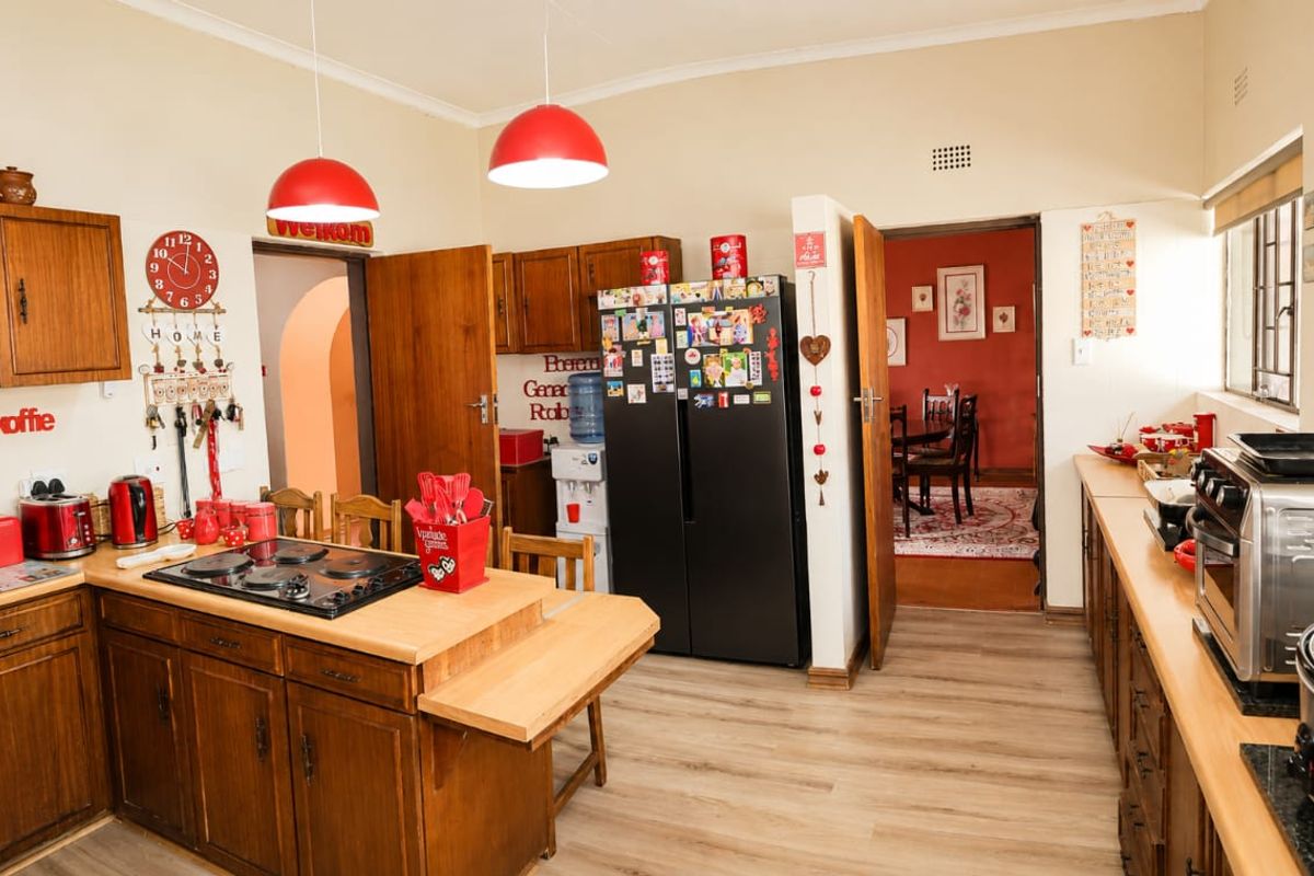 A functional kitchen featuring wooden cabinetry, a built-in hob, and laminate flooring, with an open layout connecting to the adjacent dining area.
