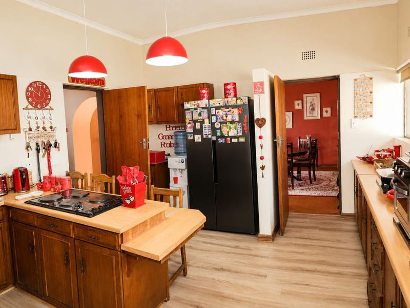 A functional kitchen featuring wooden cabinetry, a built-in hob, and laminate flooring, with an open layout connecting to the adjacent dining area.