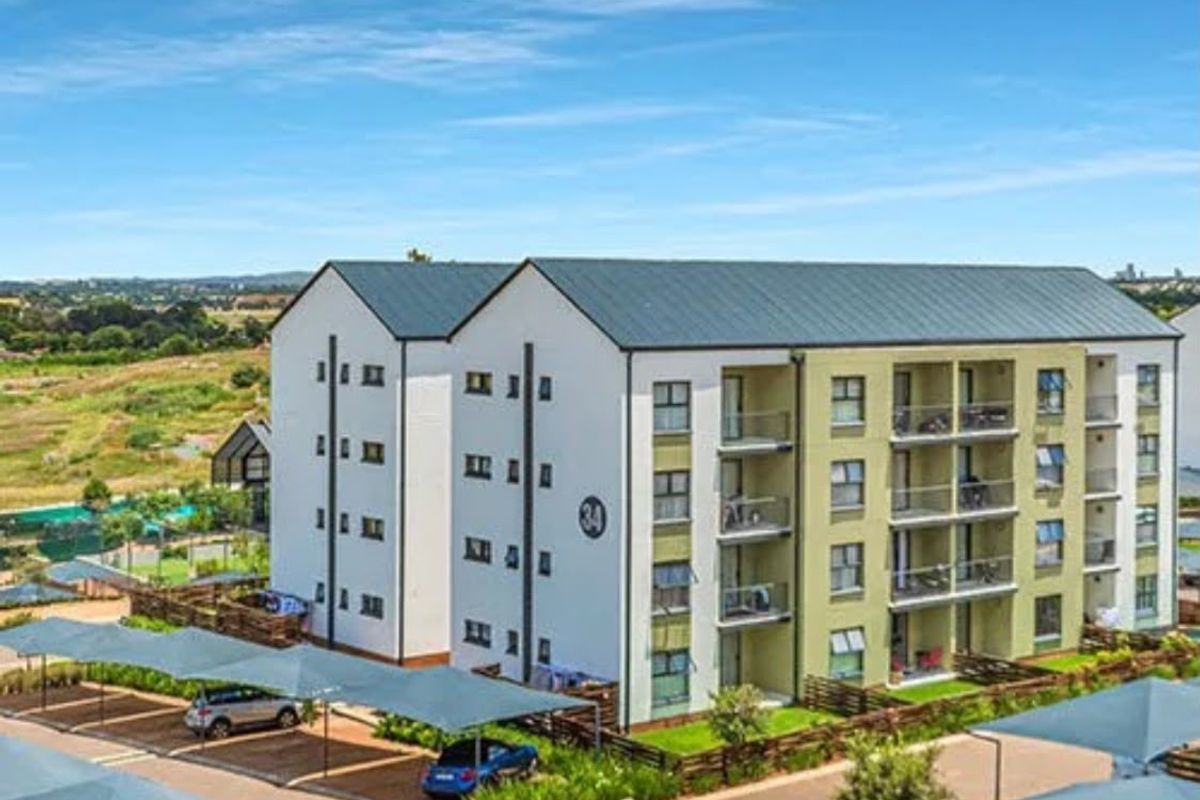 Aerial view of a modern apartment complex featuring multi-story residential blocks, private balconies, and dedicated covered parking bays within a landscaped estate.