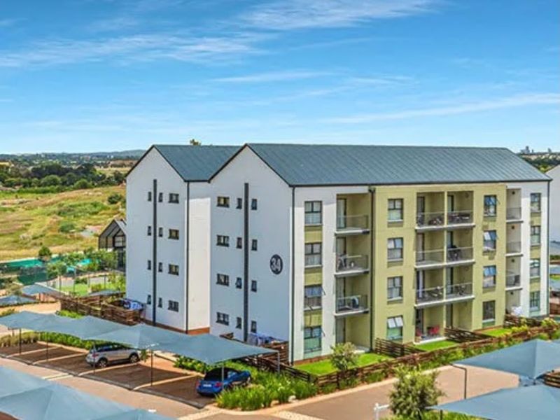 Aerial view of a modern apartment complex featuring multi-story residential blocks, private balconies, and dedicated covered parking bays within a landscaped estate.