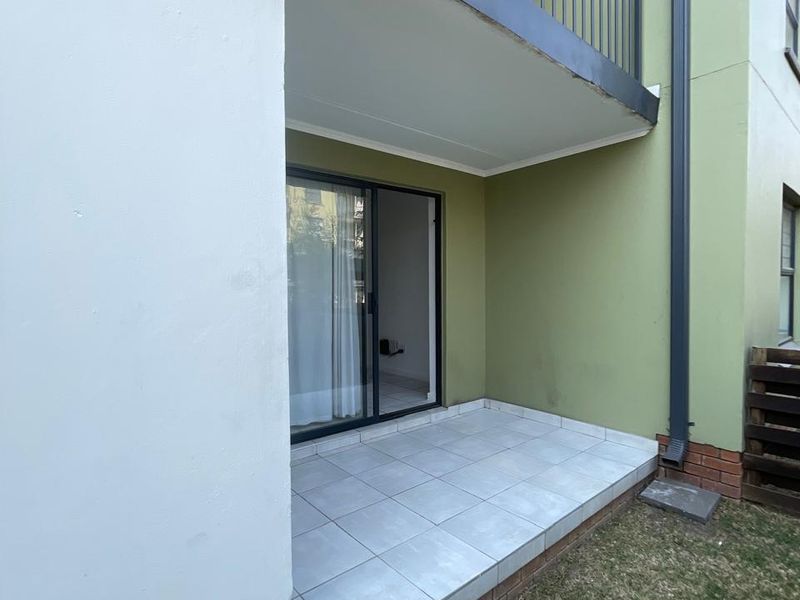 A ground floor patio featuring tiled flooring, a metal balustrade, and direct access to the interior through a sliding glass door.