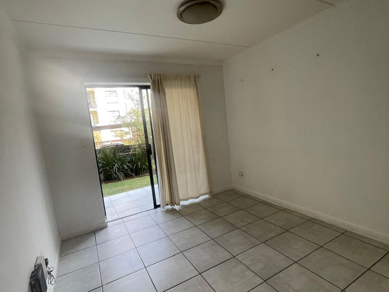 An empty living room featuring tiled flooring and a sliding glass door providing direct access to an outdoor patio area.