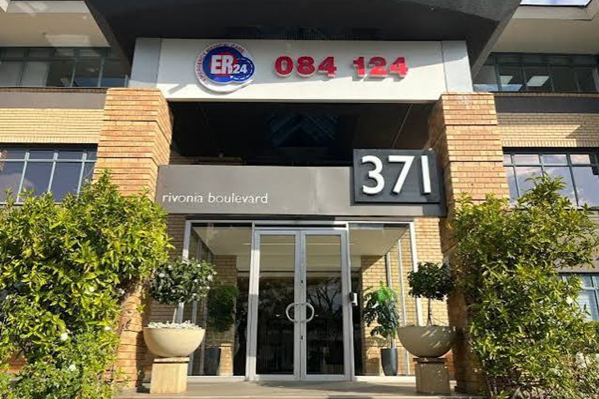 Front entrance of a commercial building featuring glass double doors, brick pillars, and prominent signage.