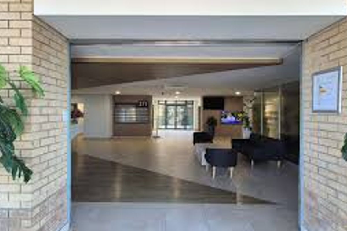 A welcoming commercial building entrance featuring a brick facade, modern tiled flooring, and a spacious lobby area with recessed lighting.