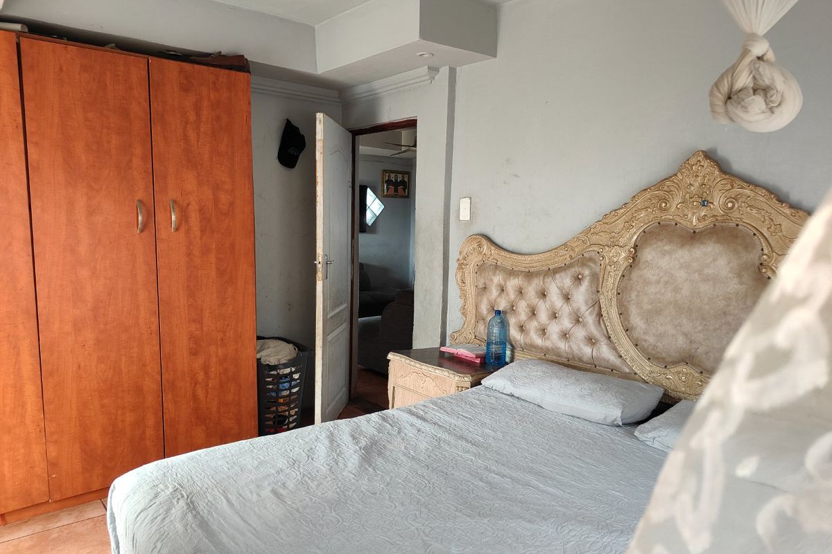 A bedroom featuring tiled flooring, a built-in wardrobe, and coved ceiling details, requiring minor cosmetic updates to improve the overall finish.