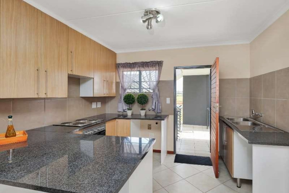 Functional kitchen featuring granite countertops, built-in cabinetry, stainless steel appliances, and tiled flooring with direct access to an outdoor balcony area.
