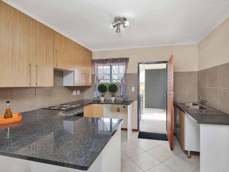 Functional kitchen featuring granite countertops, built-in cabinetry, stainless steel appliances, and tiled flooring with direct access to an outdoor balcony area.