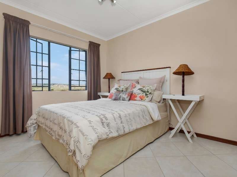 A well-maintained bedroom featuring tiled flooring, coved ceilings, and large casement windows that provide natural light and exterior views.