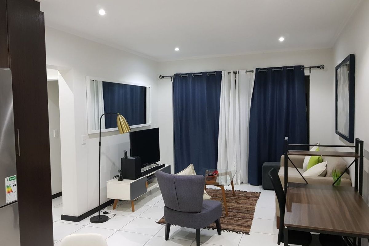 A well-maintained living room featuring neutral tiled flooring and recessed downlighting, creating a bright and functional living space.