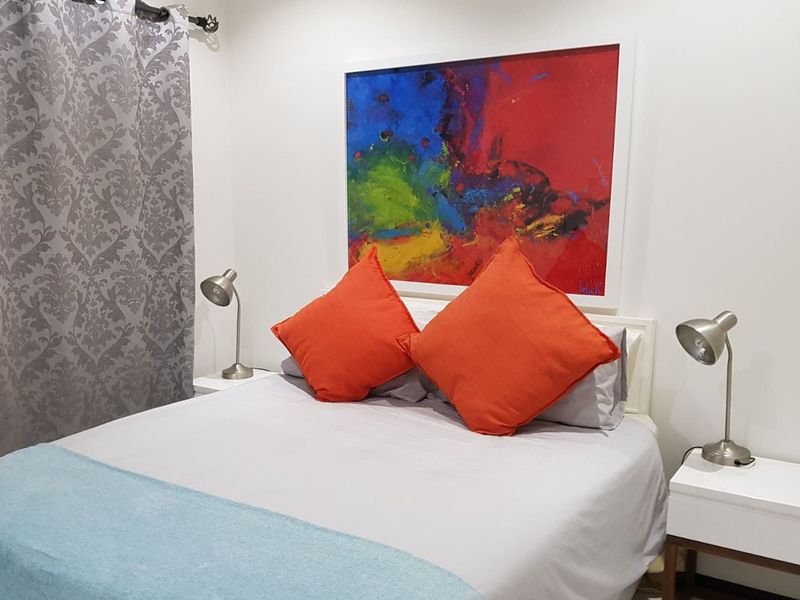 A well-maintained bedroom featuring neutral wall finishes and modern lighting fixtures.
