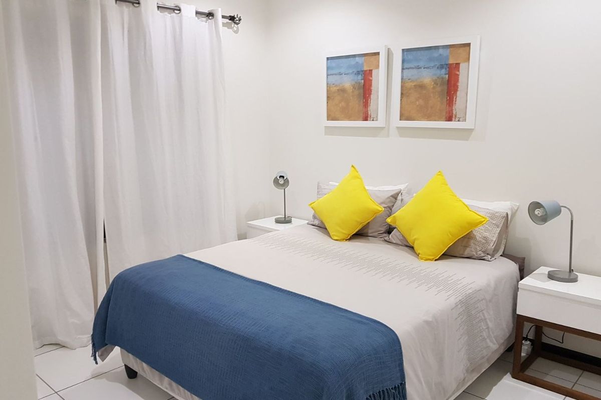 A well-maintained bedroom featuring neutral tiled flooring and white walls, providing a clean and bright living space.