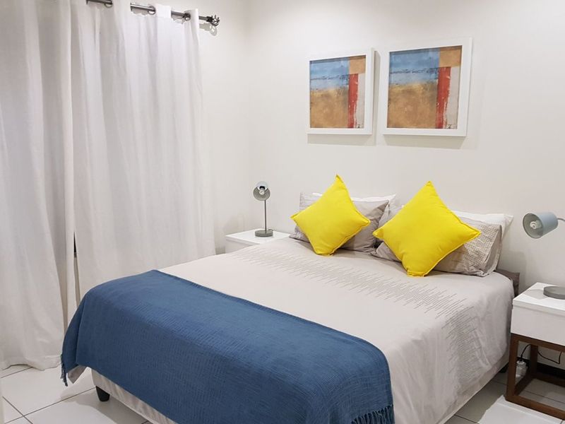 A well-maintained bedroom featuring neutral tiled flooring and white walls, providing a clean and bright living space.
