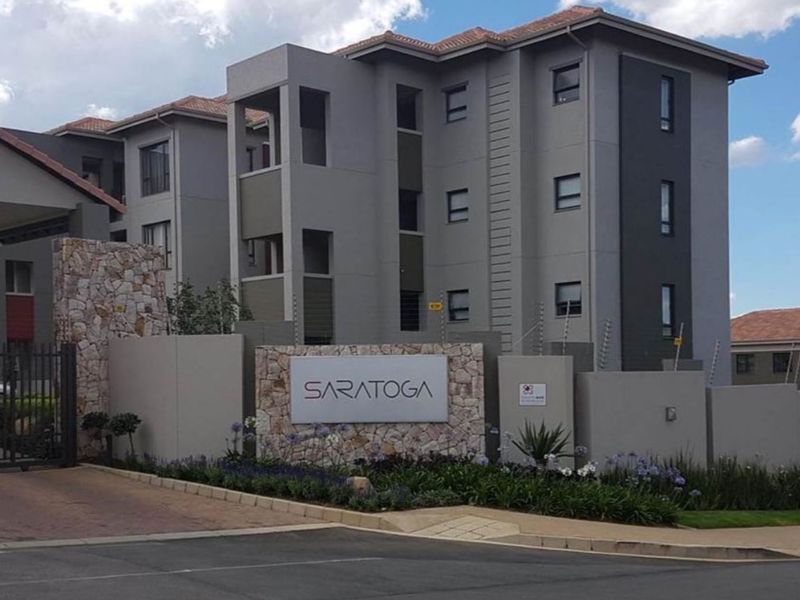 Front exterior view of the Saratoga apartment complex featuring modern grey facade, stone feature wall, and secure gated entrance.