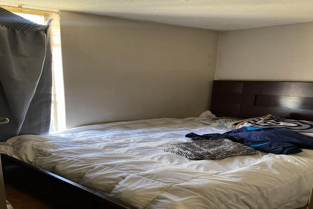 A standard bedroom featuring a window with curtains and a door, providing a functional sleeping space.