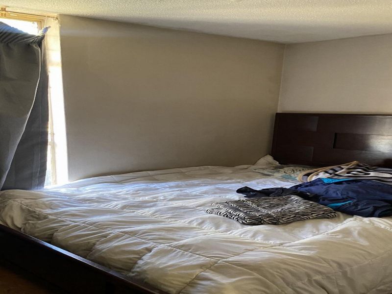 A standard bedroom featuring a window with curtains and a door, providing a functional sleeping space.