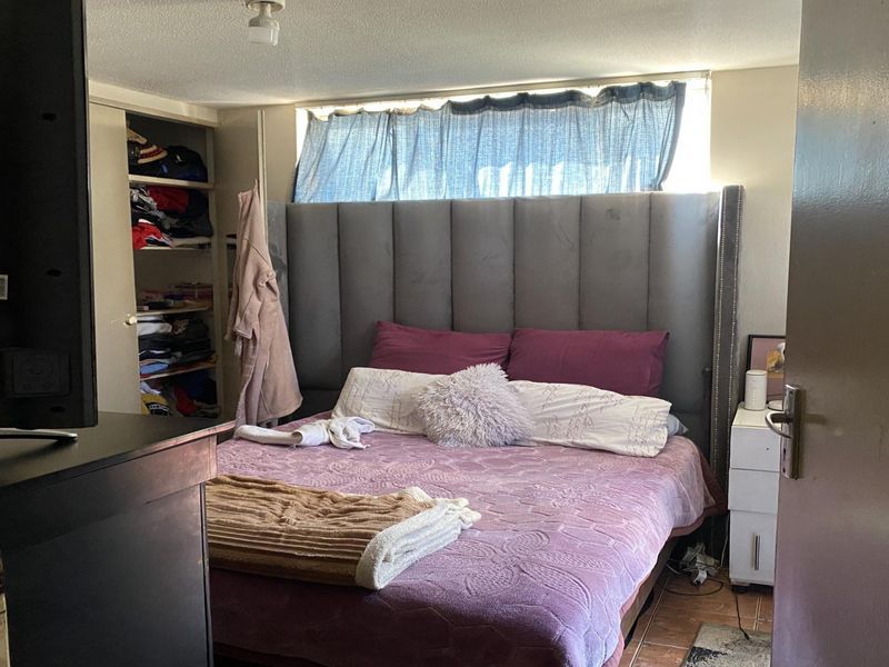 A bedroom featuring tiled flooring and a built-in wardrobe, requiring cosmetic updates to improve the overall finish and appeal.