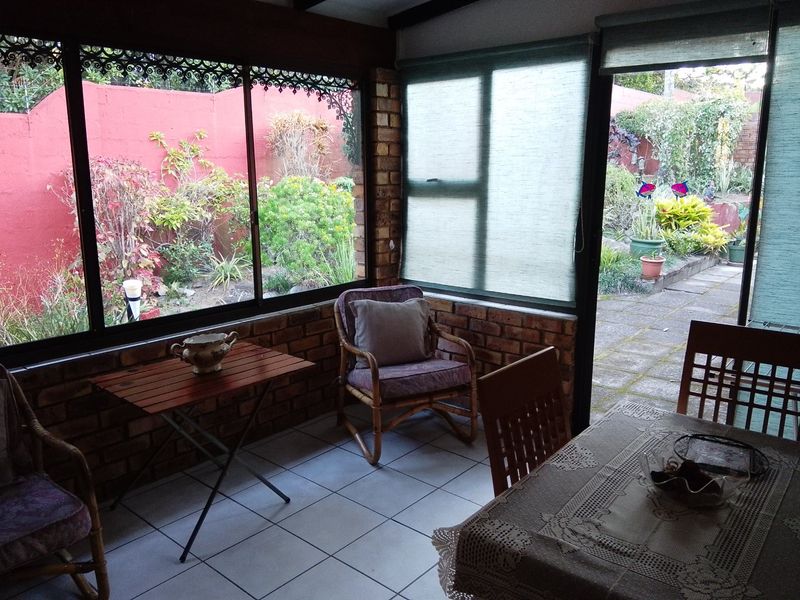 Enclosed patio area featuring exposed brick walls, tiled flooring, and large sliding glass doors providing direct access to the rear garden.
