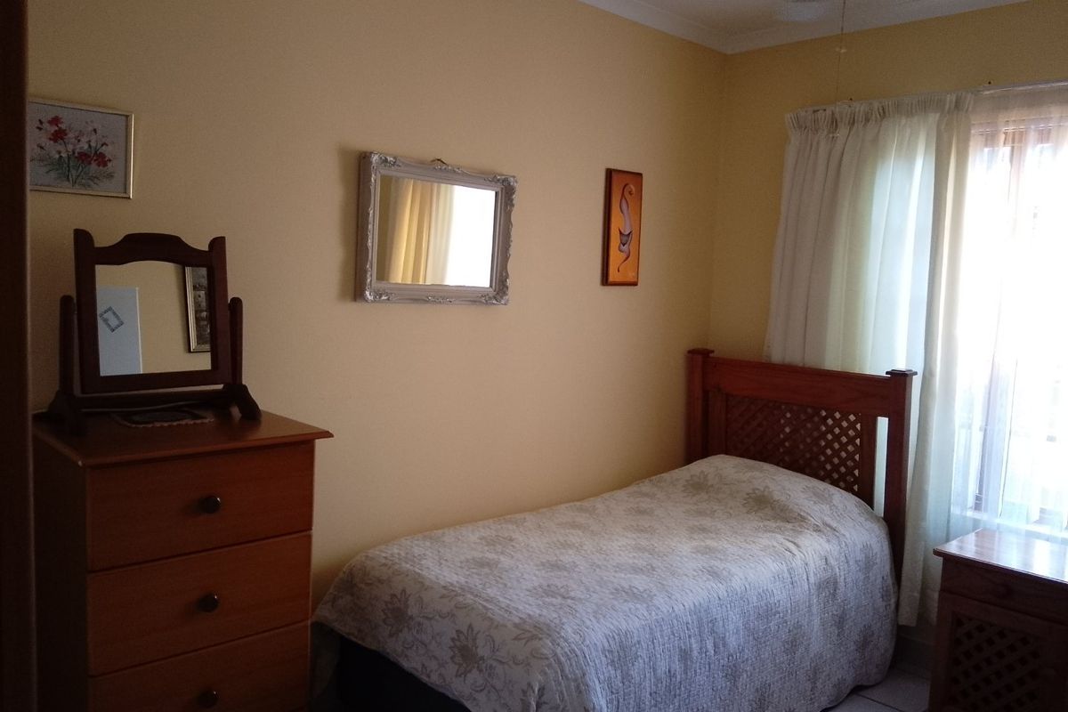 A standard bedroom featuring tiled flooring and a ceiling fan, offering a functional space with natural light from the window.
