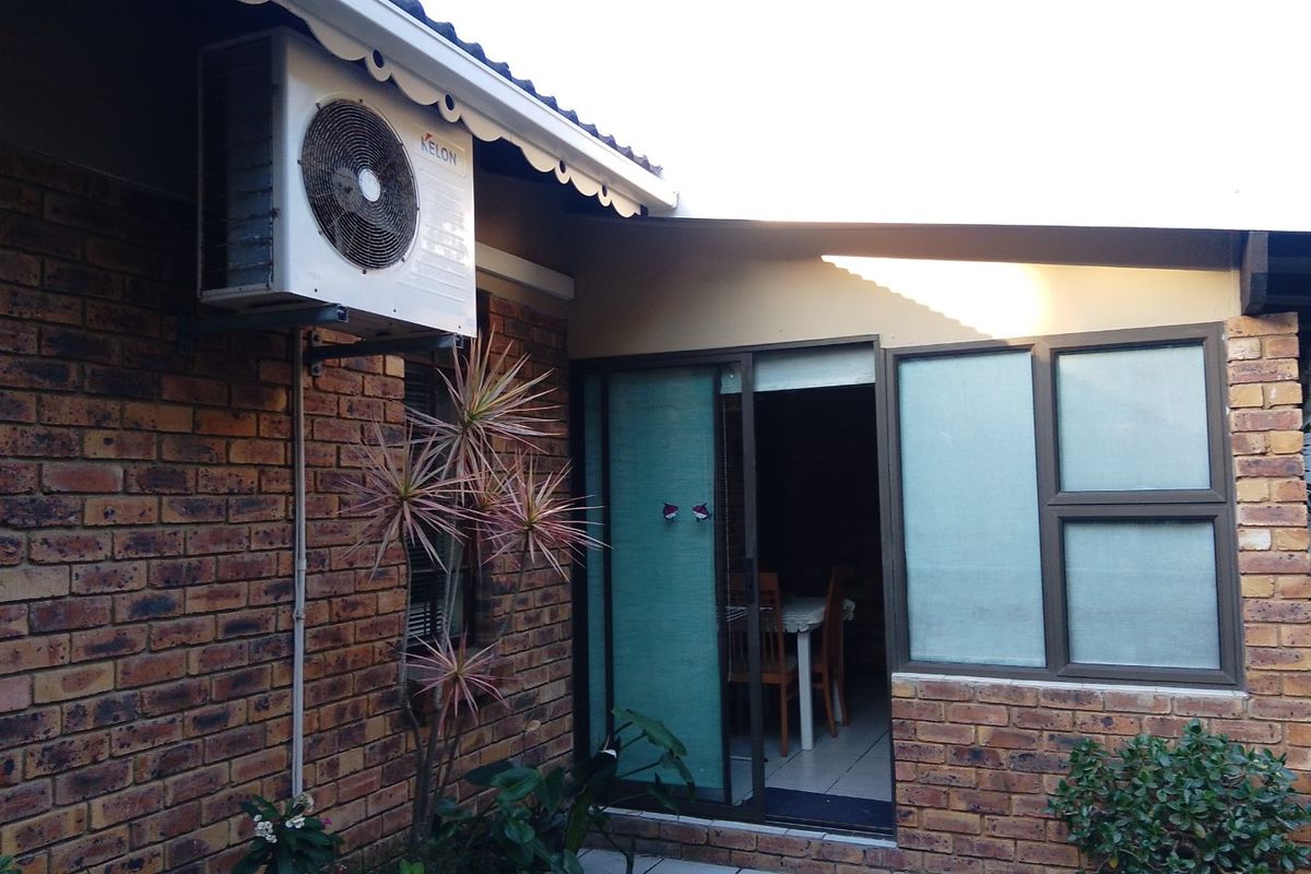 Rear exterior view of the townhouse featuring face brick walls, an installed air conditioning unit, and sliding door access to the interior living space.