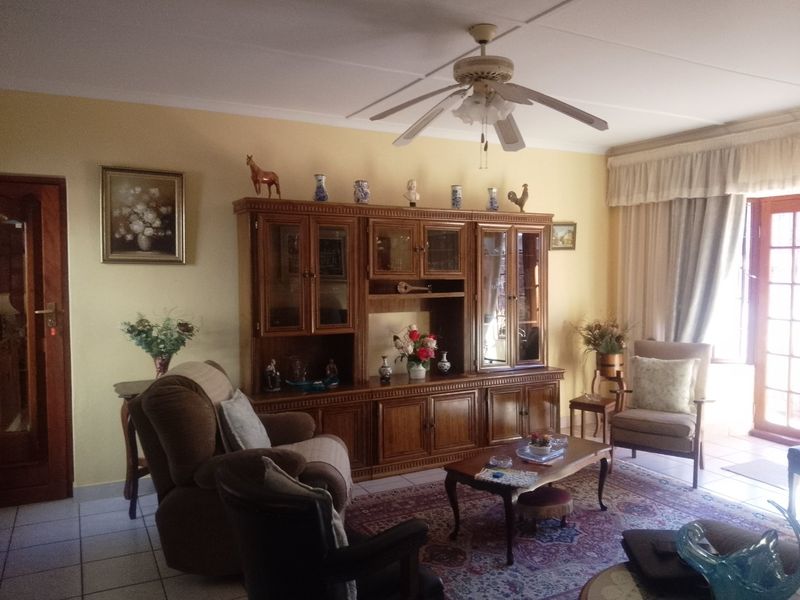 A traditional living room featuring tiled flooring, a ceiling fan, and access to an outdoor area through a timber door.