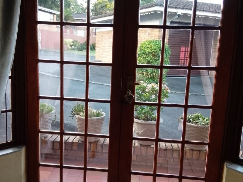 Entrance area featuring timber-framed French doors opening onto a paved exterior space with a brick threshold and tiled interior flooring.